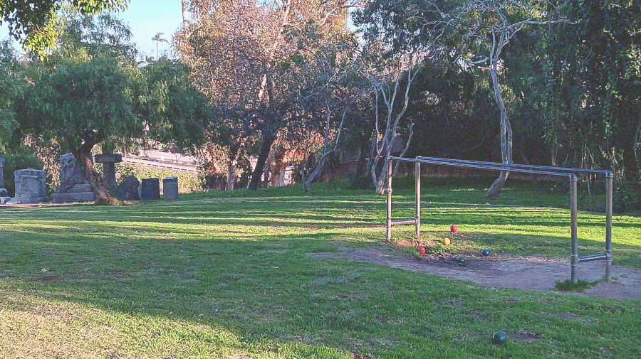 headstones and creepy vines behind parallel bars gathering bocce balls